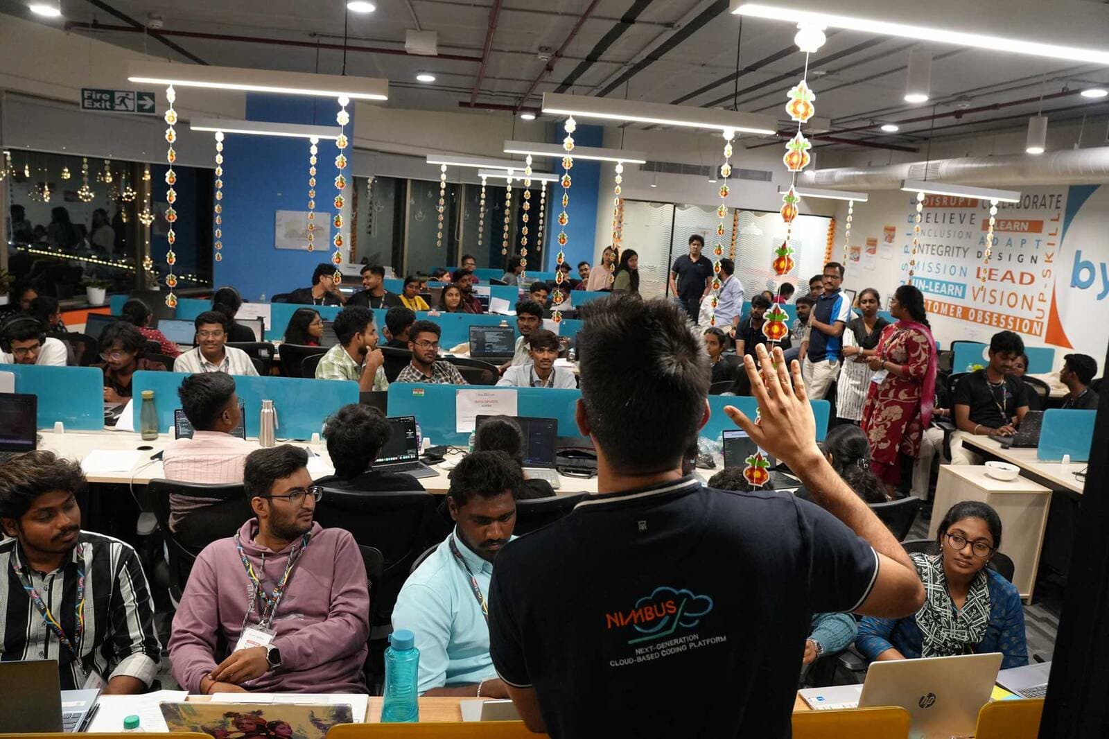 A mentor briefing teams across the coding floor